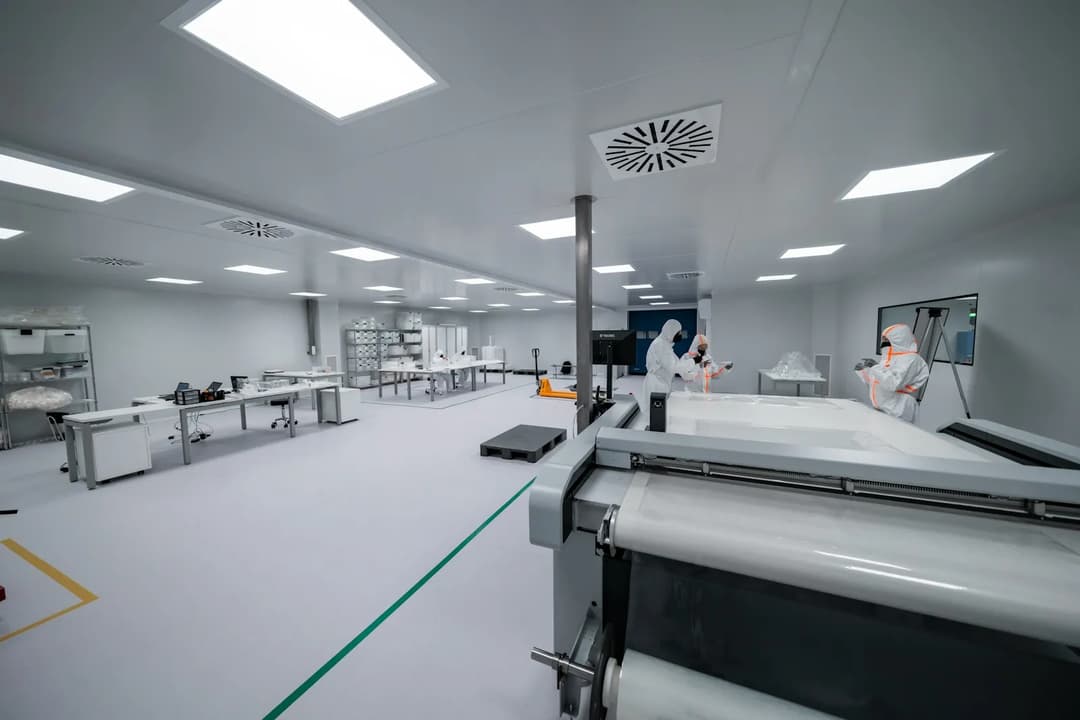 Technicians in protective suits on a clean, industrial production floor